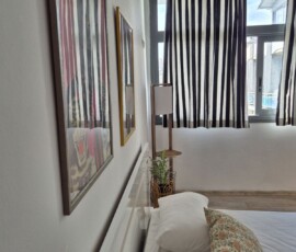 Lux studio 365 5 Λεπτομέρεια κρεβατιού με ιδιαίτερη διακόσμηση τοίχου και ριγέ κουρτίνες στο Lux Studio 365