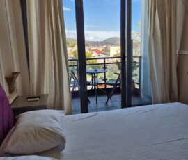 Lux Studio 365 V1 8 Διπλό κρεβάτι με ανοιχτή μπαλκονόπορτα και θέα σε τραπεζάκι εξωτερικού χώρου στο Lux Studio 365