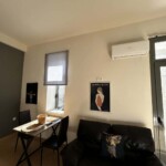 365 Studio 13 Άνετο σαλόνι με μαύρο δερμάτινο καναπέ, διακοσμητικά και έργα τέχνης, μικρό τραπέζι με καλάθι και σελοπένια, παράθυρα με φυσικό φως, και κλιματιστικό, ιδανικό για διακοπές στη Καβάλα.