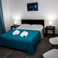 Aegean View Villa 14 Aegean View Villa – Υπνοδωμάτιο με διακριτικό φωτισμό, γαλάζια κουρτίνα και λιτή διακόσμηση