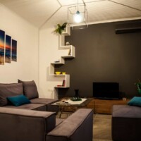 Aegean View Villa 7 Aegean View Villa – Ευρύχωρο σαλόνι με μοντέρνες ραφιέρες και φωτιστικό οροφής