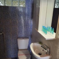 Νιπτήρας και καθρέφτης με φωτισμό σε minimal μπάνιο.