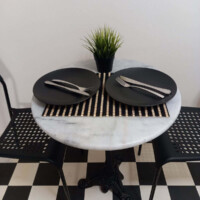 Harmony Apartment 15 Λεπτομέρεια τραπεζιού φαγητού με πιάτα και διακοσμητικό φυτό στο Harmony Apartment.